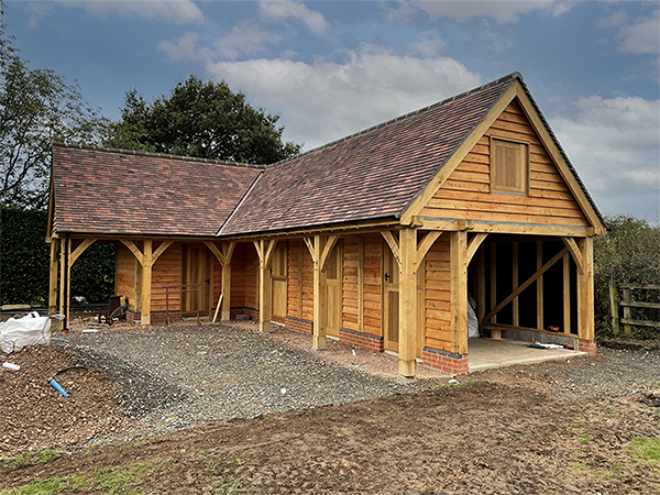 Oak framed L-shaped stable building, during construction, by Shires Oak Buildings