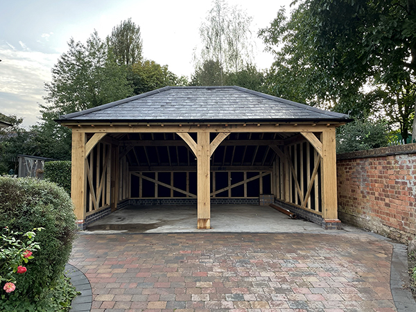 Oak framed 2 bay garage with catslide and hipped roof by Shires Oak Buildings